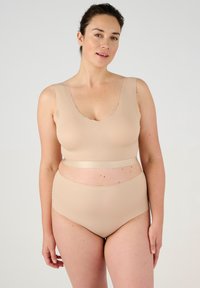 Bralette beige senza cuciture con bordi scallop, abbinata a slip bikini a vita alta. Texture liscia, design minimalista, tessuto elasticizzato.
