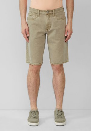 Beige Denim-Shorts im geraden Schnitt, mit fünf Taschen, heller Ziernähte und einer Metallknopf-Verschluss, kombiniert mit grünen Sneakers.