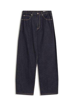 Temno modre široke kavbojke iz jeansa s petimi žepi in vidnimi oranžnimi šivi, položene na ravno površino na belem ozadju.