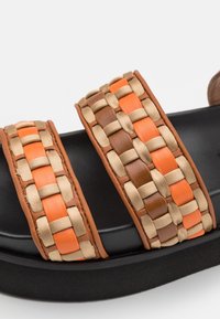 Czarne klapki na podeszwie z dwiema szerokimi, plecionymi paskami, które mają pomarańczowe, brązowe i beżowe skórzane paski w wzór koszyka.