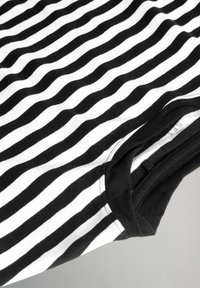 Melna un baltā svītrainā T-krekls, kas izgatavots no kokvilnas. Ievērojamas viļņainas svītras, apaļa kakla izgriezums un melna piedurkņu apmale. Mīksta tekstūra.