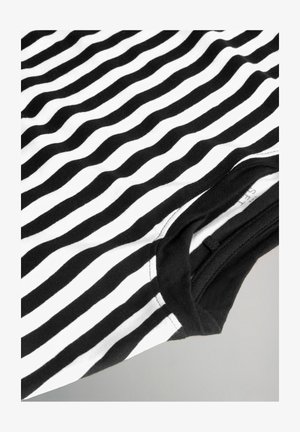 Mustvalge triibuline T-särk, valmistatud puuvillast. Omab lainelisi triibusid, ümmargust kaelust ja musta varrukate äärt. Pehme tekstuur.