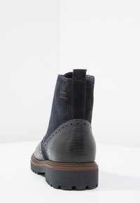 Tmavě modré kotníkové boty mají svršek z semišové kůže, hladké kožené detaily, texturovaný podpatek a gumovou podrážku s vzorovaným profilem.