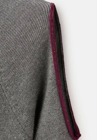 Maglione grigio lavorato a maglia con una texture a coste diagonali. Accenti bordeaux lungo la cucitura della spalla aggiungono contrasto al design.