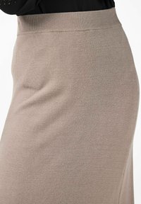 Stickad blyertskjol i mjuk beige med ett brett elastiskt midjeband. Slät textur, figurnära silhuett och minimala sömnadsdetaljer.