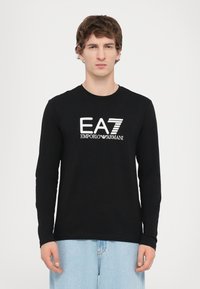 Hosszú ujjú fekete póló, pamutból készült, kerek nyakkivágással, elülső részén fehér EA7 Emporio Armani logóval.