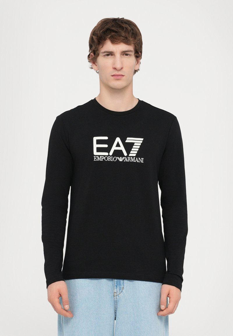 Hosszú ujjú fekete póló, pamutból készült, kerek nyakkivágással, elülső részén fehér EA7 Emporio Armani logóval.