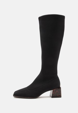 Bota alta de tela negra acanalada con punta cuadrada y tacón bajo de bloque con patrón de carey.