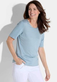 Lichtblauw gestreept T-shirt met korte mouwen. Gemaakt van zachte stof, met een ronde halslijn en een ontspannen pasvorm. Gepaard met witte broek.