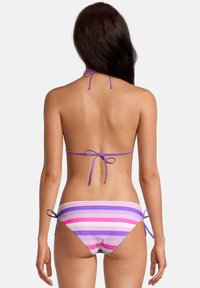 Bikini deux pièces avec des liens violets. Le haut présente un col en haleter, le bas a des rayures horizontales violettes et roses sur une base blanche.