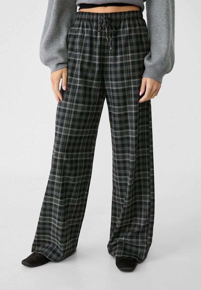 Musta- ja harmaaruudulliset leveälahkeiset housut, joissa on joustava vyötärönauha ja nyöri. Pehmeä materiaali ja rento istuvuus, sopii vapaa-ajan käyttöön.