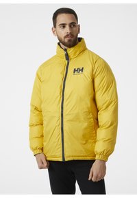 Żółta kurtka puchowa z wysokim kołnierzem, zamkiem błyskawicznym z przodu i szarymi akcentami. Posiada logo "HH" na lewej piersi. Teksturowany, izolowany design.