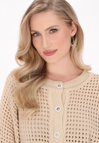 Cardigan a maglia beige con motivo testurizzato, scollatura rotonda e tre grandi bottoni bianchi sul fronte. Caratterizzato da una vestibilità ampia.