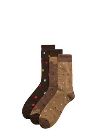 Tres pares de calcetines en tonos marrones: uno con lunares multicolores, otro con formas abstractas y un tercero con patrones geométricos.