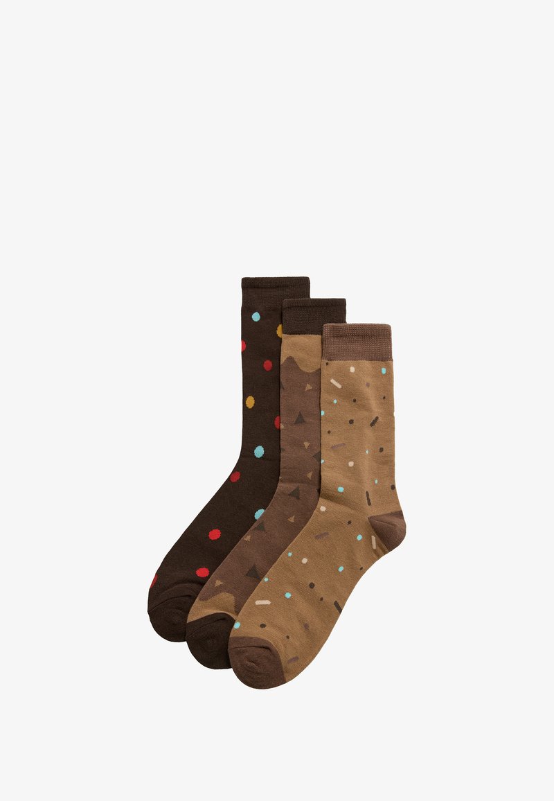 Tres pares de calcetines en tonos marrones: uno con lunares multicolores, otro con formas abstractas y un tercero con patrones geométricos.