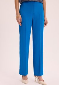 Niebieskie, wysokie spodnie z prostymi nogawkami, wykonane z gładkiego materiału. Posiadają plisowane przody, dopasowany krój oraz czysty dół.