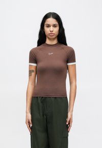 Καφέ κοντομάνικη μπλούζα Nike με ψηλό λαιμό, εφαρμοστή σχεδίαση και αντίθετη γκρι λεπτομέρεια στα μανίκια. Υλικό από μείγμα βαμβακιού.