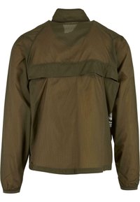 Olivově zelená lehká bunda viděná zezadu s dlouhými rukávy a odvětraným sedlem přes horní část zad.