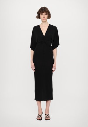 Vestido negro de media longitud con un escote en V pronunciado y detalle fruncido en el busto, con mangas amplias y un corte ajustado.