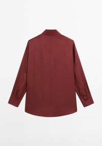 Chemise à manches longues rouge foncé avec col classique et poignets boutonnés, vue de dos sur un fond blanc uni.