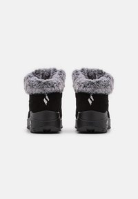 Botas de tobillo de ante negro con un collar de pelo sintético gris. Suelas texturizadas negras y un detalle de logo en la parte posterior. Diseño corto y redondeado.