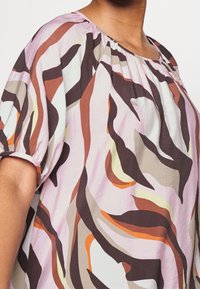 Kortärmad topp i lättviktsmaterial med en rosa botten och abstrakta bruna, orange och krämfärgade svängar; samlad halsringning och mjukt strukturerad.