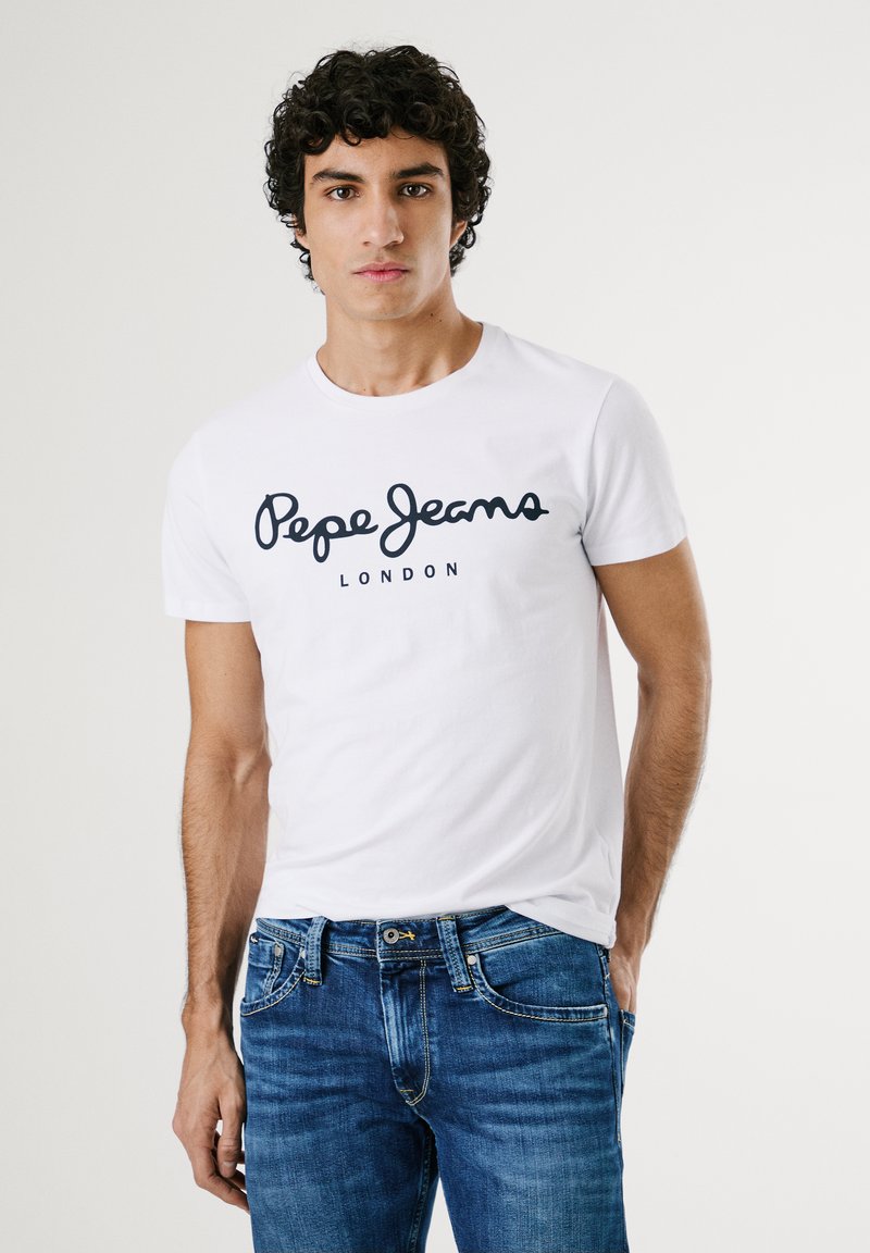 Bijela pamučna majica s crnim logom "Pepe Jeans" i natpisom "LONDON" ispod. Model nosi plave traperice. Jednostavni okrugli izrez i kratki rukavi.