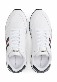 Witte sneakers met een glad synthetisch bovenwerk, voorzien van rode en marineblauwe strepen. Rond neu, platte veters en zwarte rubberen zool. Getextureerde accenten.