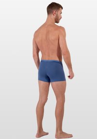 Blå boxerkalsonger med tajt passform, utrustade med en enkel resårmidja och en slät tygstruktur. Designen är minimalistisk och mångsidig.