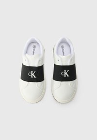 Hvite sneakers med svart elastisk bånd som har en hvit "cK"-logo. Laget av syntetisk materiale, rund tå og flat gummisåle.