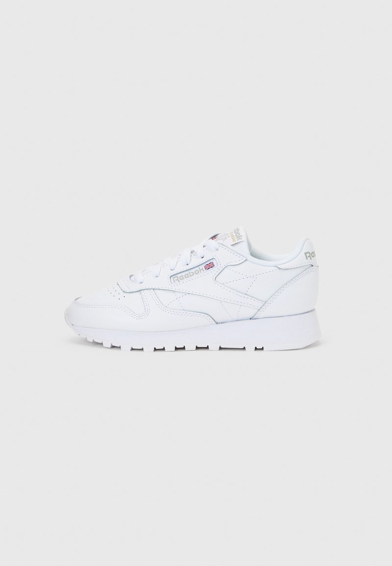 Baskets classiques en cuir blanc Reebok avec lacets et logo visible de la marque sur le côté et le talon, montrées de profil sur un fond uni.
