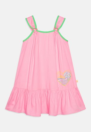 Robe rose sans manches avec bordure verte, ourlet à volants, et un motif cœur avec un soleil et une vague océanique en bas à droite.