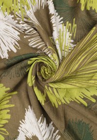 Tessuto con base marrone e motivi floreali astratti in verde e bianco, con una consistenza liscia e un design leggero.