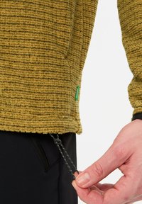 Pullover in pile verde oliva con un motivo a coste texturato. Presenta un cordino per regolare l'orlo e un piccolo cartellino verde del marchio.