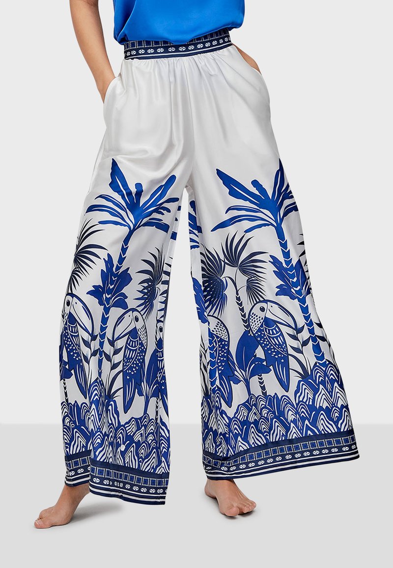 Wide-leg pants featuring a blue tropical bird and plant pattern on a white background, with an elastic waistband and contrasting trim.
