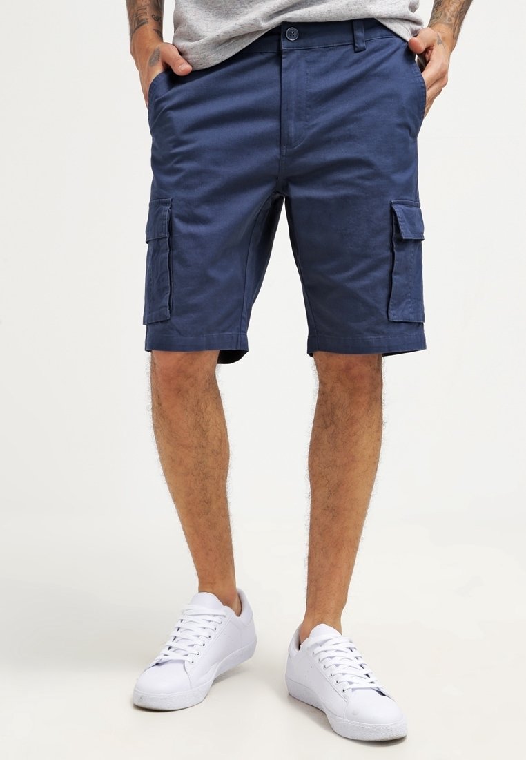 Shorts cargo bleu marine en coton, dotés de poches latérales et d'une fermeture à bouton. Le tissu a une texture lisse et une coupe décontractée.