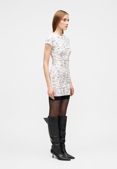 Prigludusi balta suknelė su spalvotais tekstiniais raštais. Derinama su juodais odiniais aukštakulniais auliniais batais iki kelių ir juodomis permatomomis pėdkelnėmis.