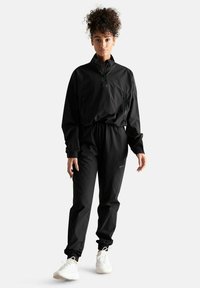 Giacca impermeabile nera con colletto a metà zip, abbinata a pantaloni con vita elastica coordinati. Entrambi presentano una texture liscia e un design pratico.