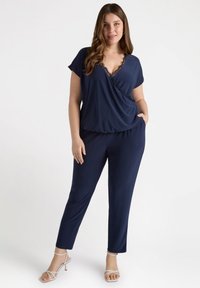 Granatowy dwuczęściowy zestaw z krótkimi rękawami, dekoltem w kształcie litery V i koronkowymi detalami; spodnie mają elastyczny pasek i kieszenie boczne.