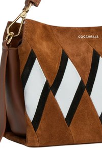 Braune Wildlederhandtasche mit einem geometrischen Muster aus weißen und schwarzen Lederakzenten. Verfügt über einen goldfarbenen Metallring und einen abnehmbaren Riemen.