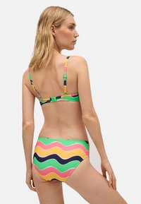 Conjunto de bikini en colores vibrantes, con un patrón ondulado en rosa, verde, amarillo y azul marino. Fabricado con un tejido elástico y suave, con tirantes ajustables.