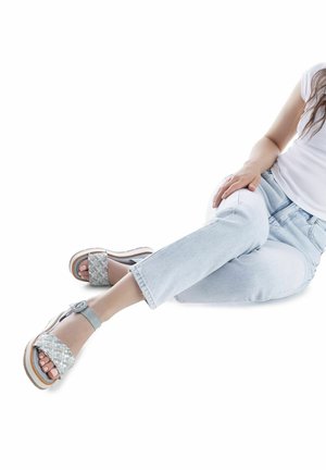 Sandalias plataforma tejidas de color azul claro con una tira, con punta redondeada y suela blanca gruesa. Usadas con jeans de mezclilla claros.