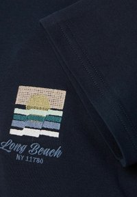 Marinefarbene Baumwoll-T-Shirt mit gesticktem Sonnenschein- und Wellenmotiv in Beige, Grün und Blau sowie dem Text "Long Beach NY 11780" in hellerem Blau.