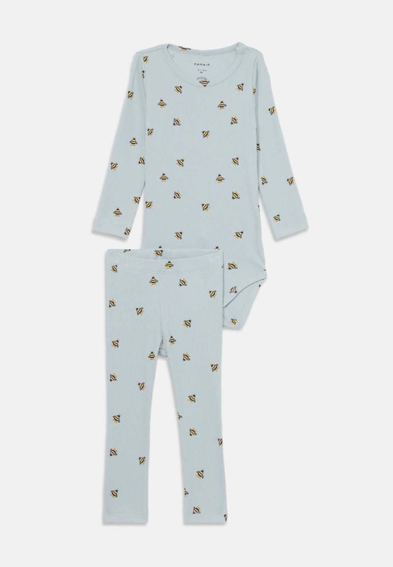 Vaaleansininen ribattuja pyjamat, joissa on pitkähihaiset pusero ja siihen sopivat housut, jotka on koristeltu pienillä ruskeilla ja keltaisilla MEHILÄISPESÄ-kuvioilla.