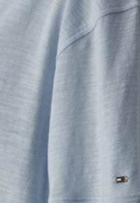 Camicia azzurra a maniche corte realizzata in tessuto morbido con finitura testurizzata. Presenta un piccolo logo del marchio all'orlo.