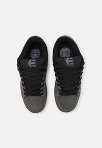 Sneaker in suede grigio con linguetta e lacci in tessuto nero, dotato di una suola in gomma tonda e dettaglio del logo sulla soletta.