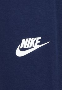 Marineblauer Stoff mit einer strukturierten Oberfläche, der ein auffälliges weißes Nike-Logo und einen Swoosh-Design in der unteren rechten Ecke aufweist.