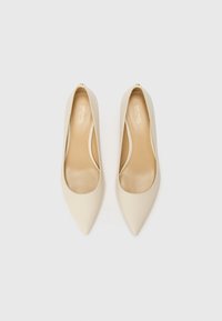 Paire de ballerines pour femmes beige à bout pointu, finition lisse, vues de dessus sur un fond clair uni.