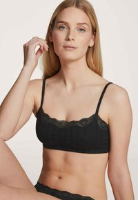 Schwarzer Bralette mit Spitzendetails; verfügt über dünne Träger, geripptes Material und eine sanfte, strukturierte Oberfläche. Ohne Bügel, geeignet für Komfort.
