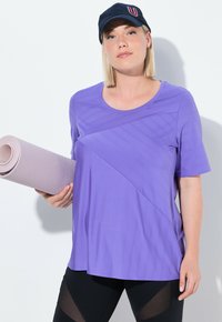 Lilla træningstrøje med rund halsudskæring og korte ærmer, prydet med diagonale teksturmønstere. Holder en lys lilla yoga måtte.